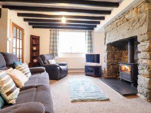 a living room with a couch and a stone fireplace at Bryn Re in Trawsfynydd