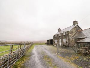 an old house on a dirt road next to a fence at Bryn Re in Trawsfynydd