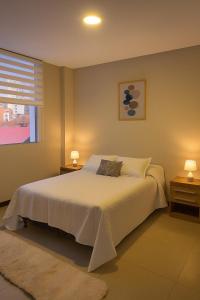a bedroom with a bed with two night stands and a window at Departamento en barrio Petrolero in Sucre
