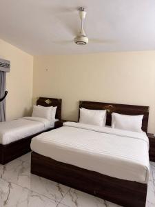 a bedroom with two beds with white sheets and a ceiling at Signature Boutique Hotel Karachi in Karachi