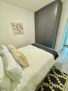 a bedroom with a bed with white sheets and pillows at Waterfall Smart Apartment 2bed2bath in Midrand +11 photos