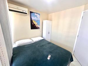 una piccola camera da letto con un letto con una coperta verde di Eu Amo Arraial Hospedagem - Prainha 3 Quartos com Ar condicionado ad Arraial do Cabo