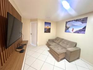 un soggiorno con divano e TV a schermo piatto di Eu Amo Arraial Hospedagem - Prainha 3 Quartos com Ar condicionado ad Arraial do Cabo