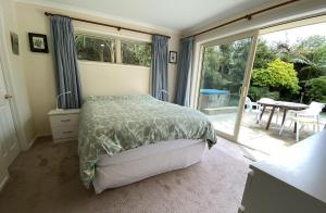 une chambre avec un lit et un balcon avec une table dans l'établissement Private Coastal Sanctuary - 50m from Stunning Beach!, à Whakatane
