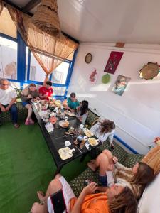 un groupe de personnes assises autour d'une table en train de manger dans l'établissement TISLIT Surf Taghazout, à Taghazout