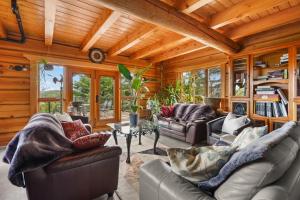 a living room with leather furniture and wooden ceilings at Hébergement "La Maison en Bois Rond" in Sainte-Marie
