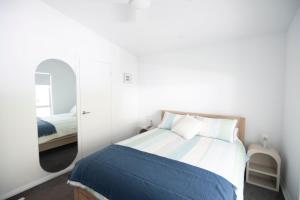 a bedroom with a bed and a mirror at Tranquil 3-Bed Home Pet-friendly Retreat with Community Pool in St Georges Basin