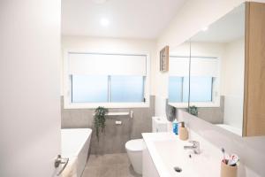 a white bathroom with a sink and a toilet at Tranquil 3-Bed Home Pet-friendly Retreat with Community Pool in St Georges Basin +9 photos