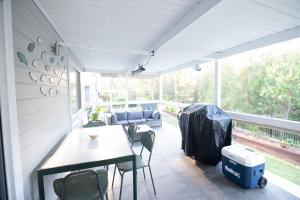 a screened in porch with a table and chairs at Tranquil 3-Bed Home Pet-friendly Retreat with Community Pool in St Georges Basin