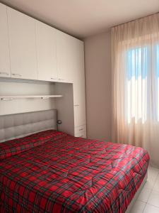 a bedroom with a bed with a plaid blanket at Maison della Presolana in Songavazzo