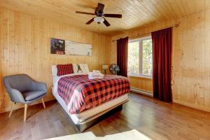 a bedroom with a bed and a ceiling fan and a chair at The Dreamer - Skiing - Spa - Outdoor and Relaxation in Petite-Rivière-Saint-François