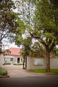 un edificio con un árbol delante de él en Abiento Guesthouse, en Bloemfontein