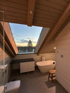 a bathroom with a large window and a bath tub at Naava Chalet Penthouse - Kattohuoneisto järvinäköalalla in Ähtäri