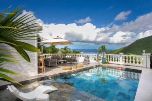 a swimming pool with chairs and an umbrella at Villa Princess sea view private pool Anse Marcel in Saint Martin