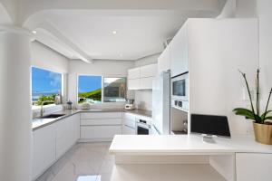 a kitchen with white cabinets and a desk with a computer at Villa Princess sea view private pool Anse Marcel in Saint Martin