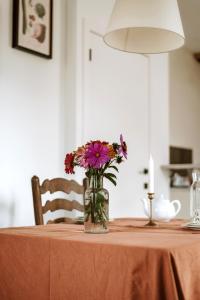 een vaas met bloemen bovenop een tafel bij Gîte de la maraîchère in Ittre
