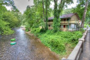 a house on the side of a river next to a road at Hofbrau Riverfront Hotel in Helen