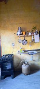 a kitchen with a stove and a shelf with pots and pans at Abrigo Quixadá in Quixadá