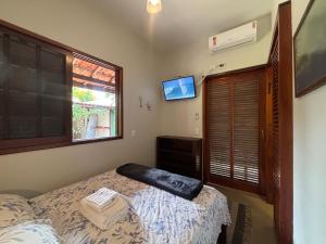 een slaapkamer met een bed, een raam en een televisie bij Itamambuca Suites in Ubatuba