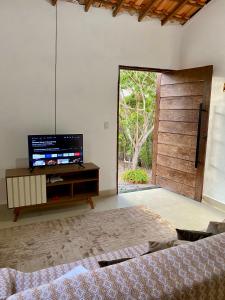 1 dormitorio con TV y puerta corredera de cristal en Casa Lilás no Vale do Capão, en Vale do Capao