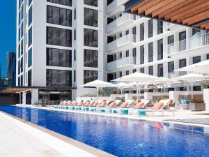 ブリスベンにあるThe Johnson Brisbane - Art Seriesのラウンジチェアとパラソルのあるホテルのプール