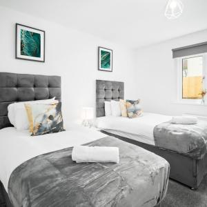 deux lits dans une chambre aux murs blancs dans l'établissement Modern 2Bed Apartment - Netflix - Parking 55C, à Sleightholme