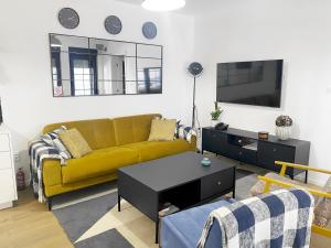 een woonkamer met een gele bank en een tv bij Petite Mansion in Nasicz