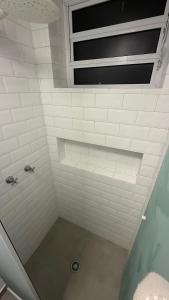 a white tiled shower with a window in a bathroom at Charmosa hospedagem no Jardim Secreto SP in Sao Paulo