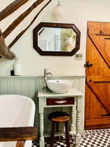 ein Badezimmer mit Waschbecken und Spiegel in der Unterkunft Fairytale Cottage in the Country in Hornton + 132 Fotos