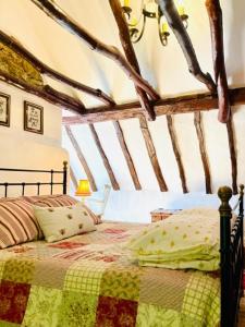 ein Schlafzimmer mit einem Bett mit einer Steppdecke darauf in der Unterkunft Fairytale Cottage in the Country in Hornton