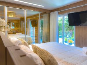 een slaapkamer met een groot bed en een televisie bij Mont Ararat Alto da Pitinga - Rede Tonziro in Porto Seguro