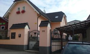 ein rosa Haus mit einem schwarzen Zaun und einem Auto in der Unterkunft Villa Amenity in Světlá nad Sázavou