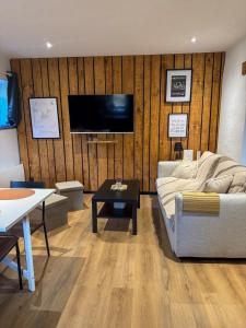 Una sala de estar con un sofá y un televisor en una pared. en A Cybiclette, en Saint-Étienne-lès-Remiremont