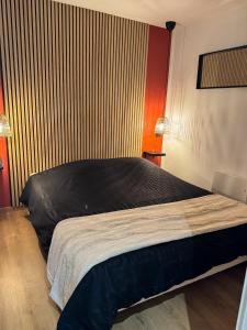 1 dormitorio con cama negra y pared de madera en A Cybiclette, en Saint-Étienne-lès-Remiremont