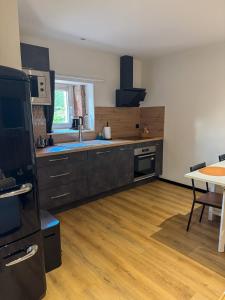 una cocina grande con suelo de madera y una mesa en A Cybiclette, en Saint-Étienne-lès-Remiremont