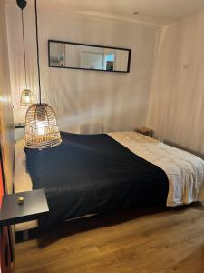 Un dormitorio con una cama con una manta negra y un espejo. en A Cybiclette, en Saint-Étienne-lès-Remiremont 5 fotos más