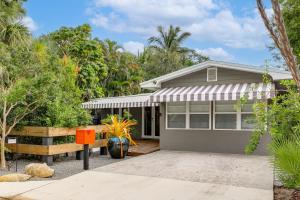 a house with a porch and trees in front of it at 1 Mi to Lake Worth Beach Park Poolside Paradise! in Lake Worth