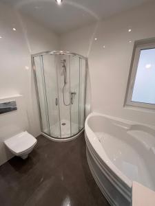 a bathroom with a shower and a toilet and a tub at Domy całoroczne Cieszyno in Cieszyno