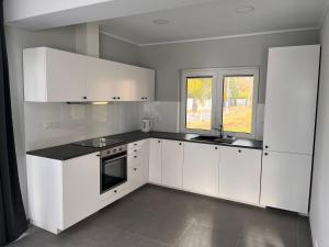 a kitchen with white cabinets and a black counter top at Domy całoroczne Cieszyno in Cieszyno