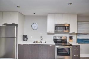 Una cocina con gabinetes blancos y electrodomésticos de acero inoxidable. en Clifton Hill Hideaway 2b -two Bedroom Condo, en Niagara Falls 3 fotos más