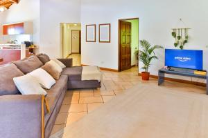 a living room with a couch and a flat screen tv at Blue Horizon - La Villa Sora - Pool - Sea view in Punaauia
