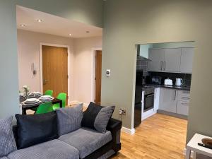 a living room with a couch and a table and a kitchen at Apollo Apartment at Edgerton Suites in Huddersfield