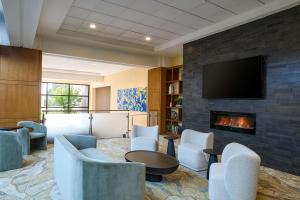 a lobby with a fireplace and chairs and a tv at Detroit Marriott Troy in Troy