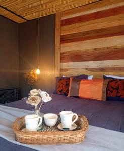 a tray with cups and flowers on a bed at Brasa Loft de Campo in Colonia Las Rosas