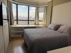 a bedroom with a bed and a large window at Flat mobiliado em Campinas - Ap 124 L Hirondelle in Campinas