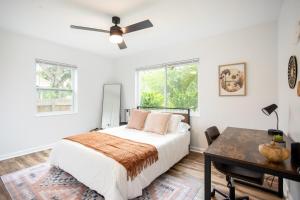 a bedroom with a bed and a desk and windows at Dog Friendly - 8min to Downtown - FAST Wifi in St Petersburg