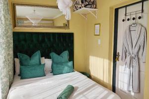 1 dormitorio con cama con almohadas verdes y espejo en Budget Stays at Olivia Pines Guesthouse, en Krugersdorp