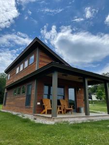 a log cabin with two chairs on the porch at Gorgeous Cabin Getaway on a Farm in Windsor County, Vermont in Sheddsville