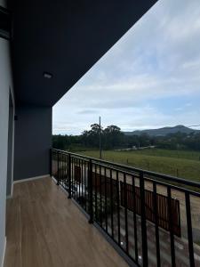a balcony with a view of a green field at Tua Casa no Rosa in Imbituba