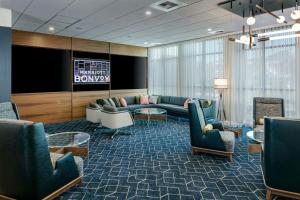 a waiting room with couches and chairs and a television at Courtyard Lewiston in Lewiston